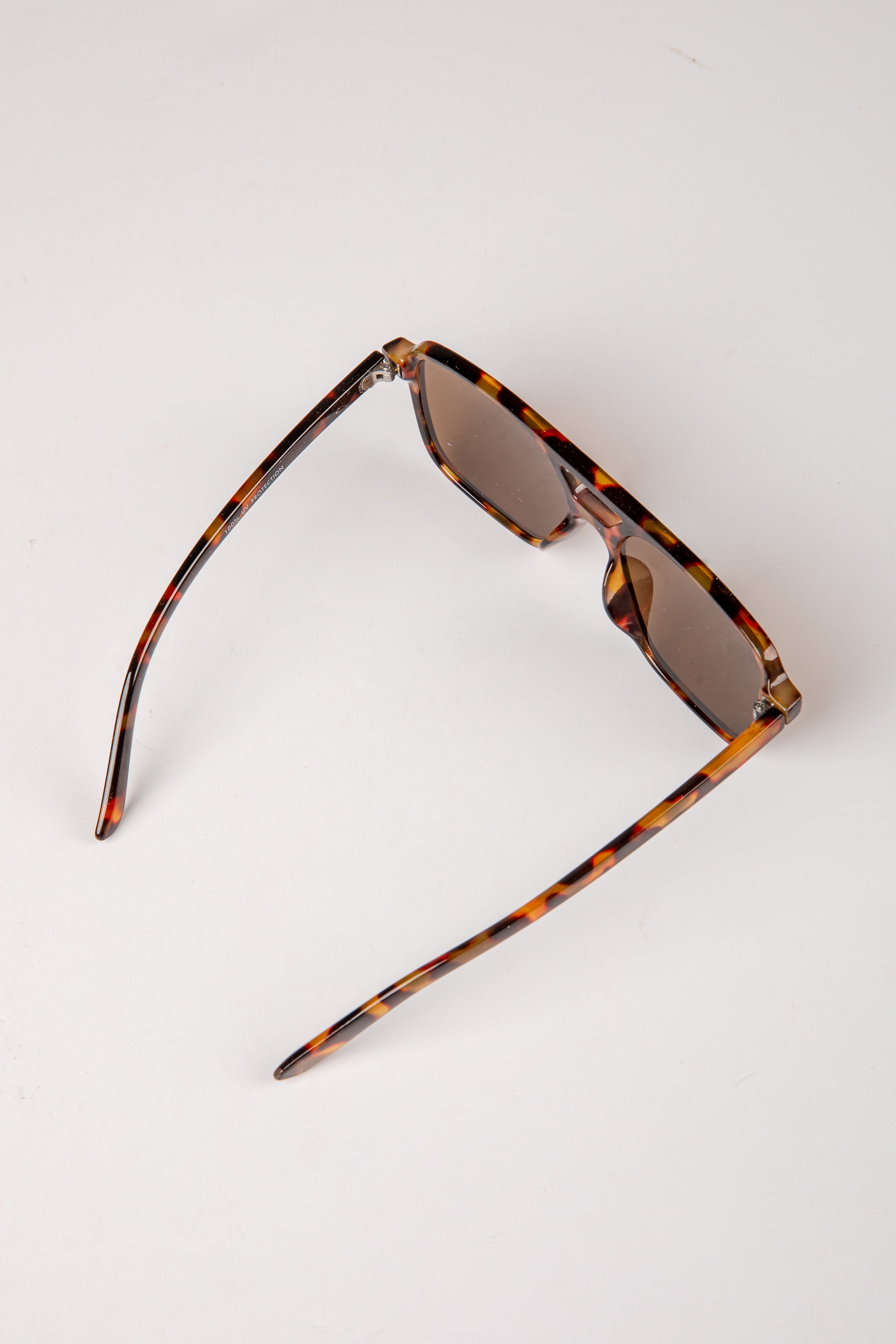 Sunglasses with tortoiseshell frame and dark lenses on a white background