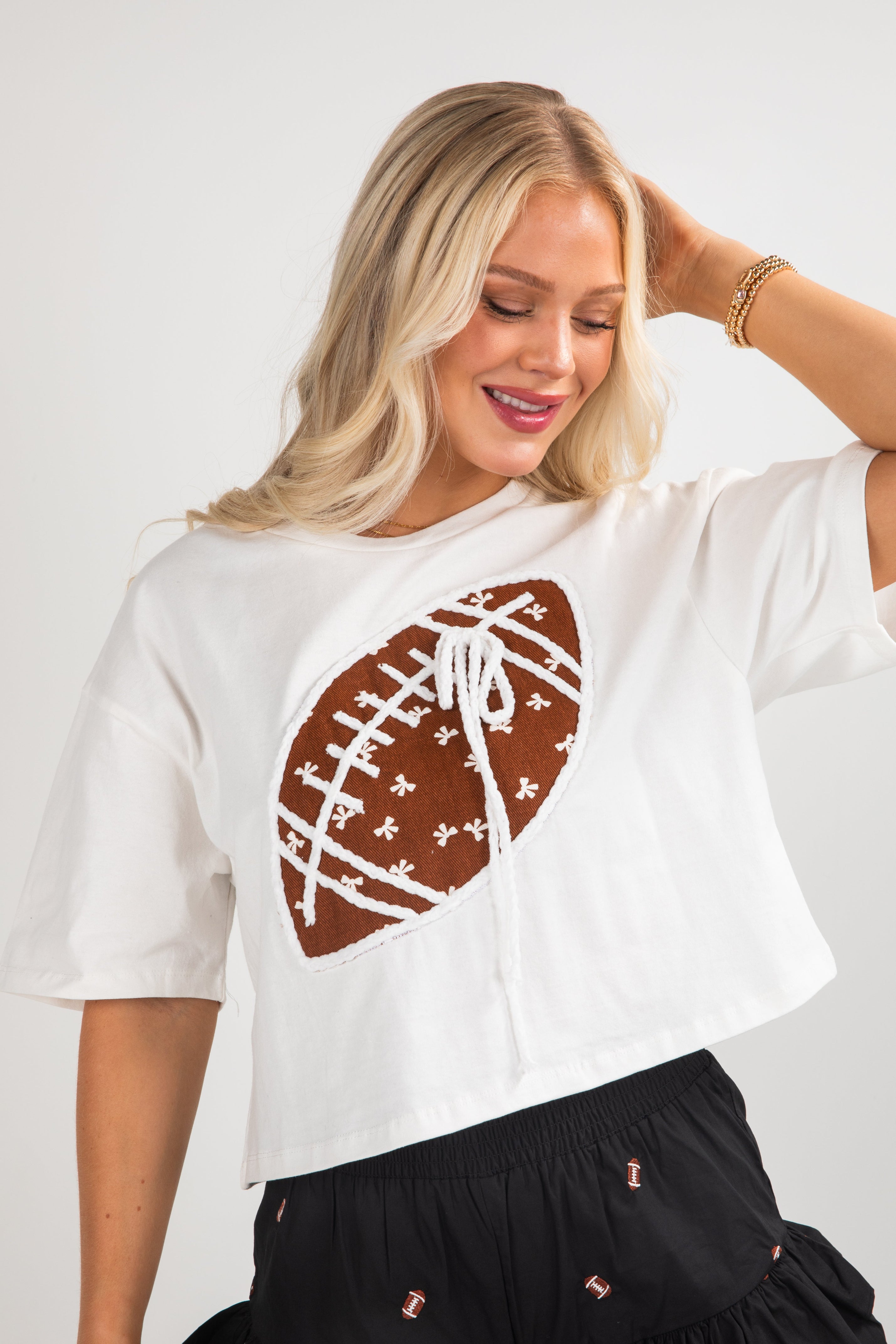 Woman wearing a white t-shirt with a brown football graphic on a plain background