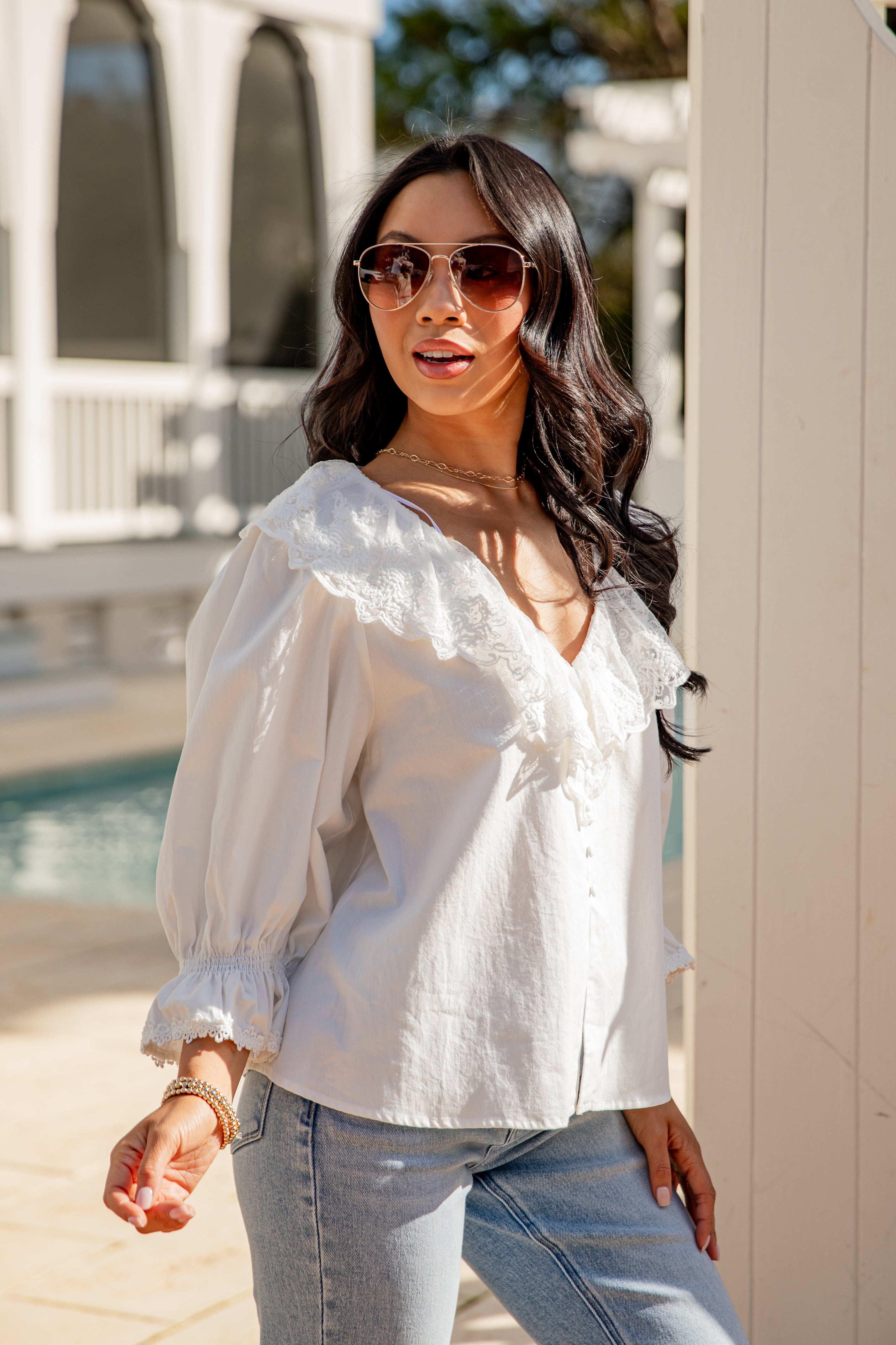 Woman wearing a white blouse and sunglasses outdoors