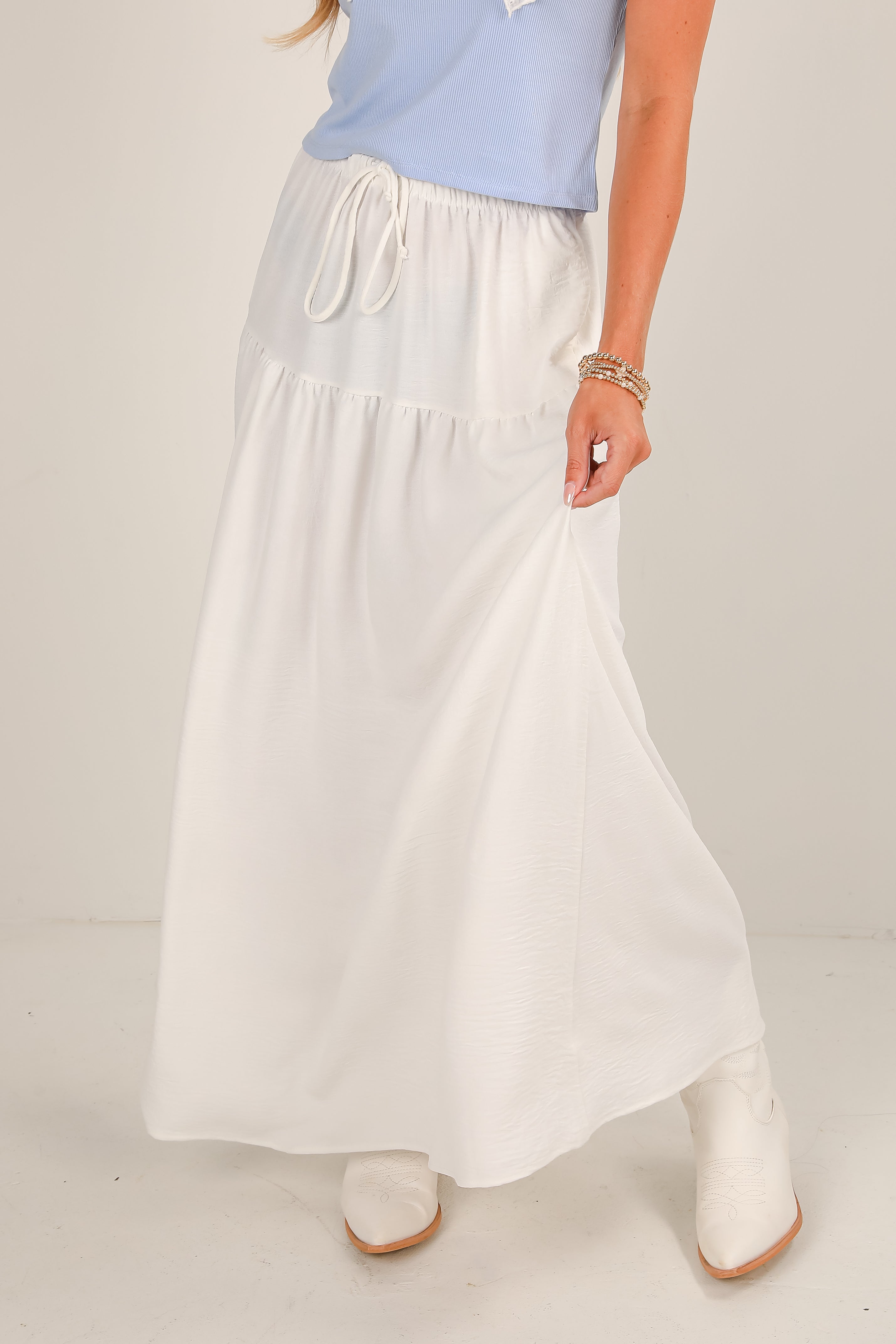 Person wearing a light blue top and white skirt on a plain background