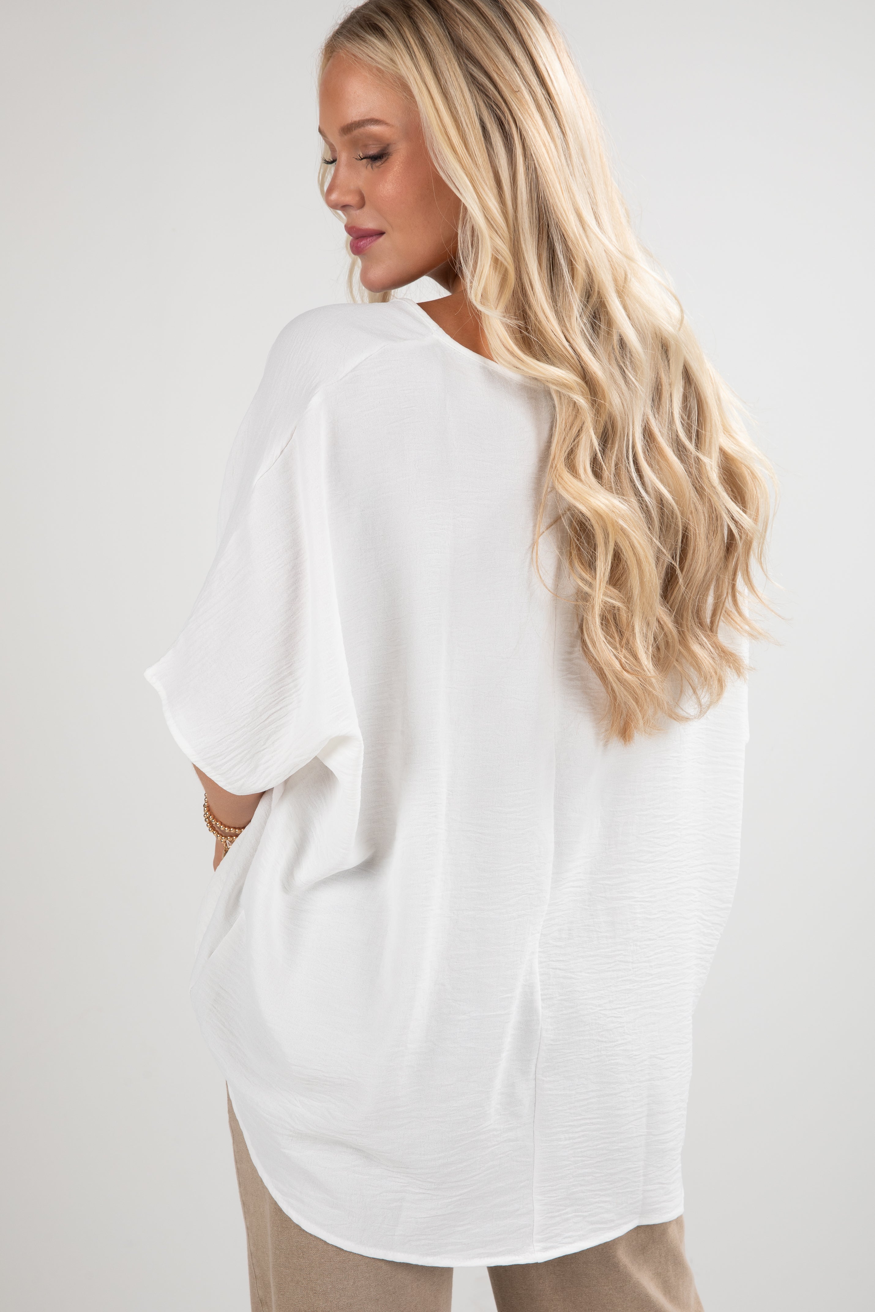 Woman wearing a white oversized shirt with a plain background