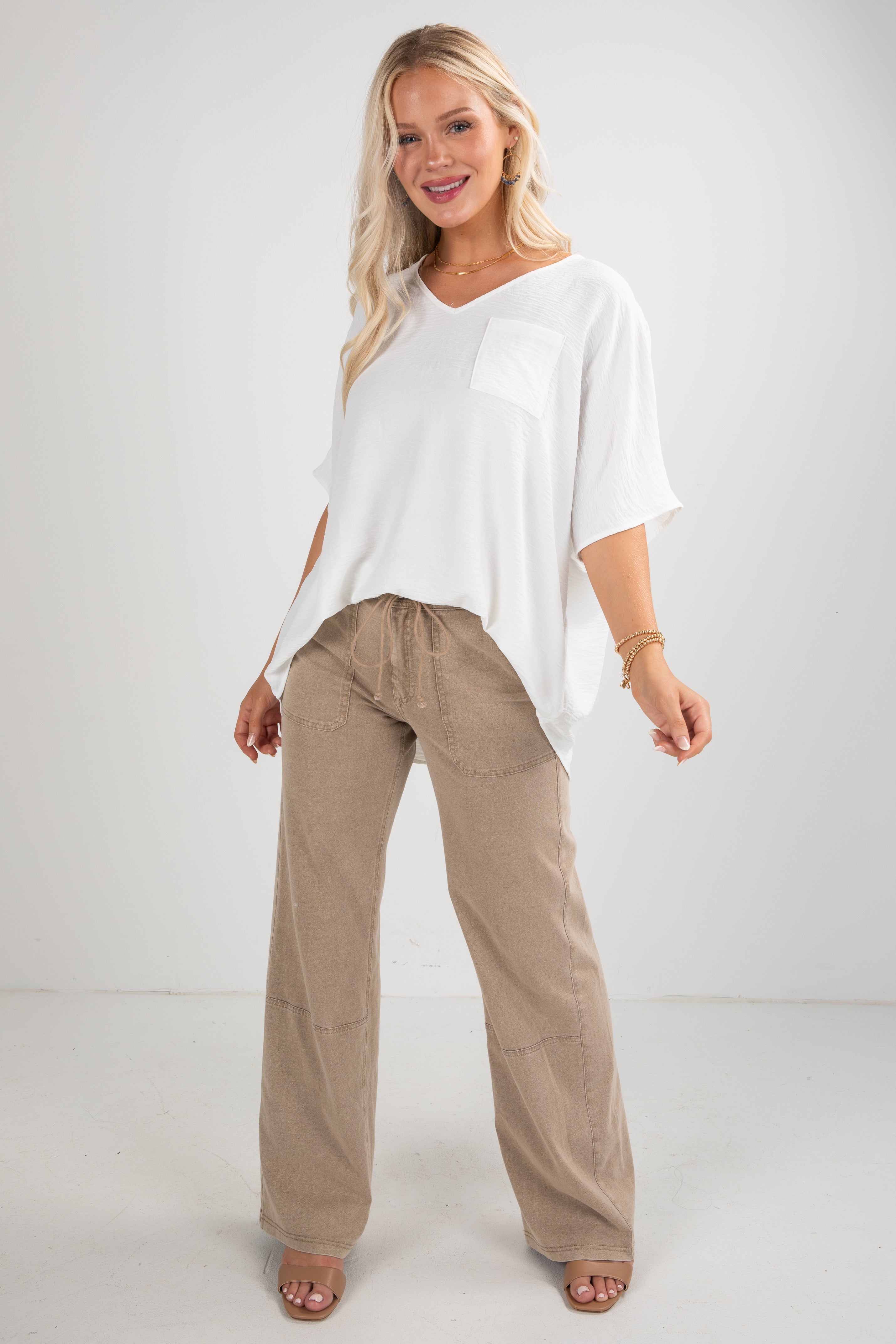 Woman wearing a white top and beige pants on a white background