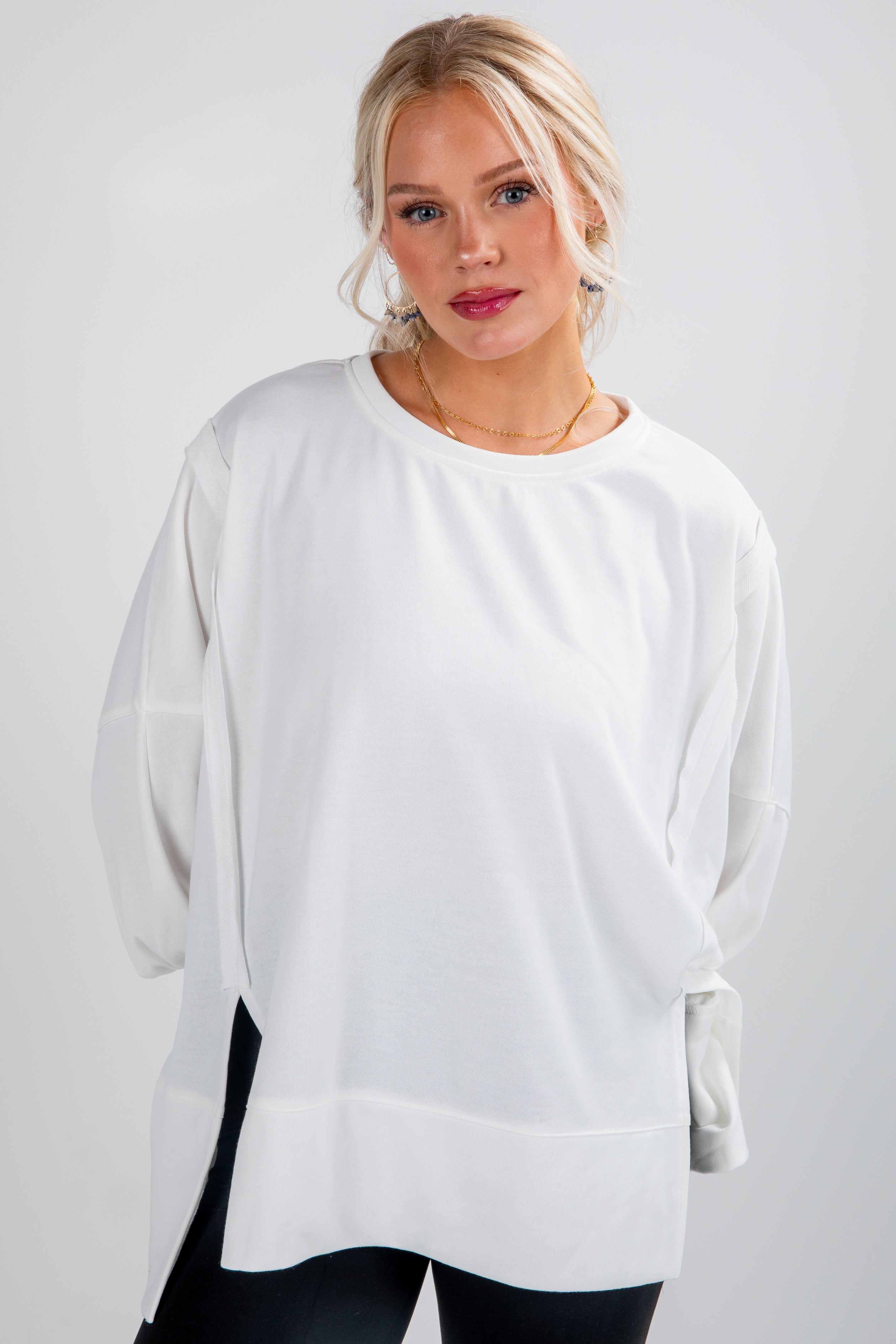 Woman wearing a white oversized sweater on a plain background