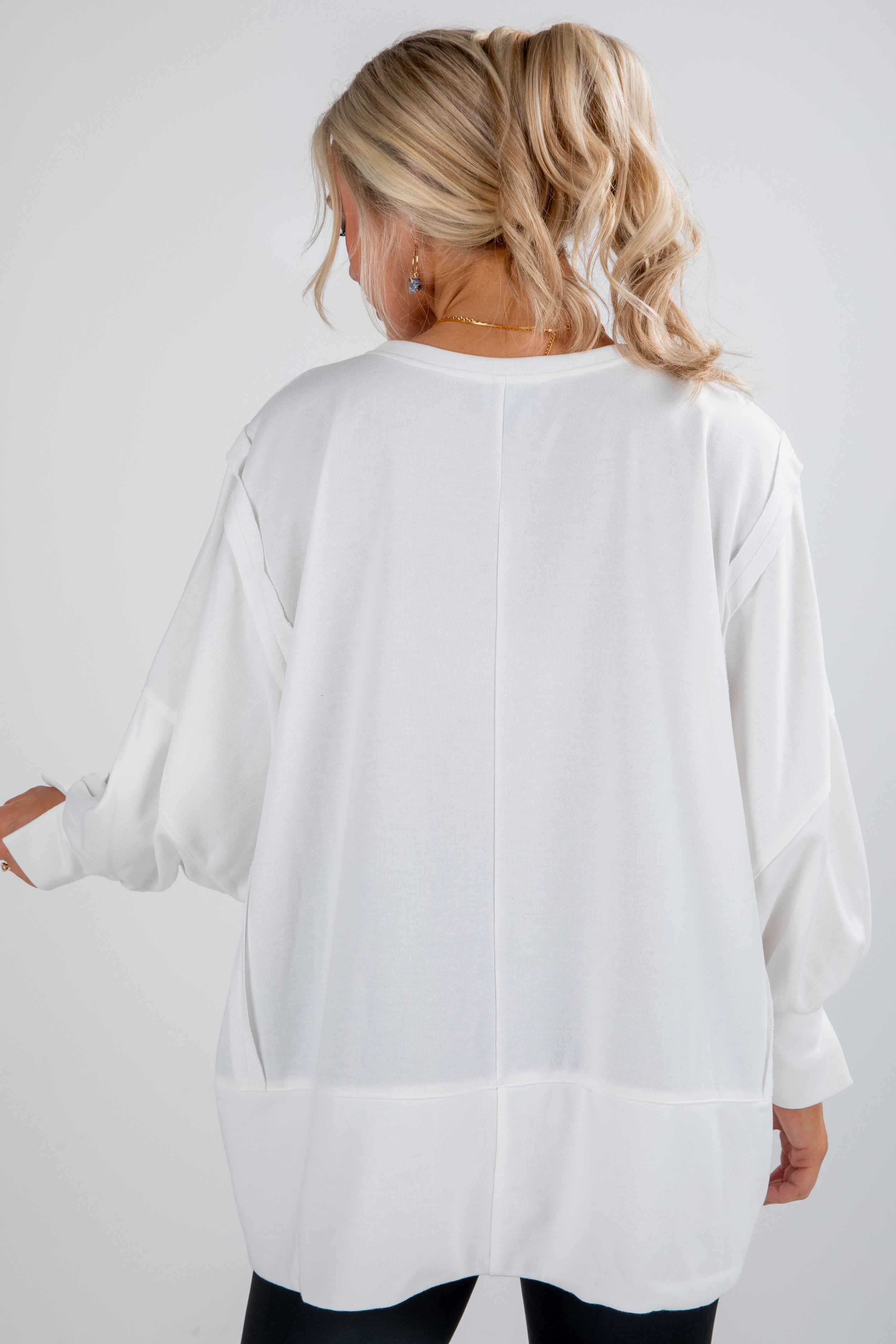Woman wearing a white oversized shirt on a plain background