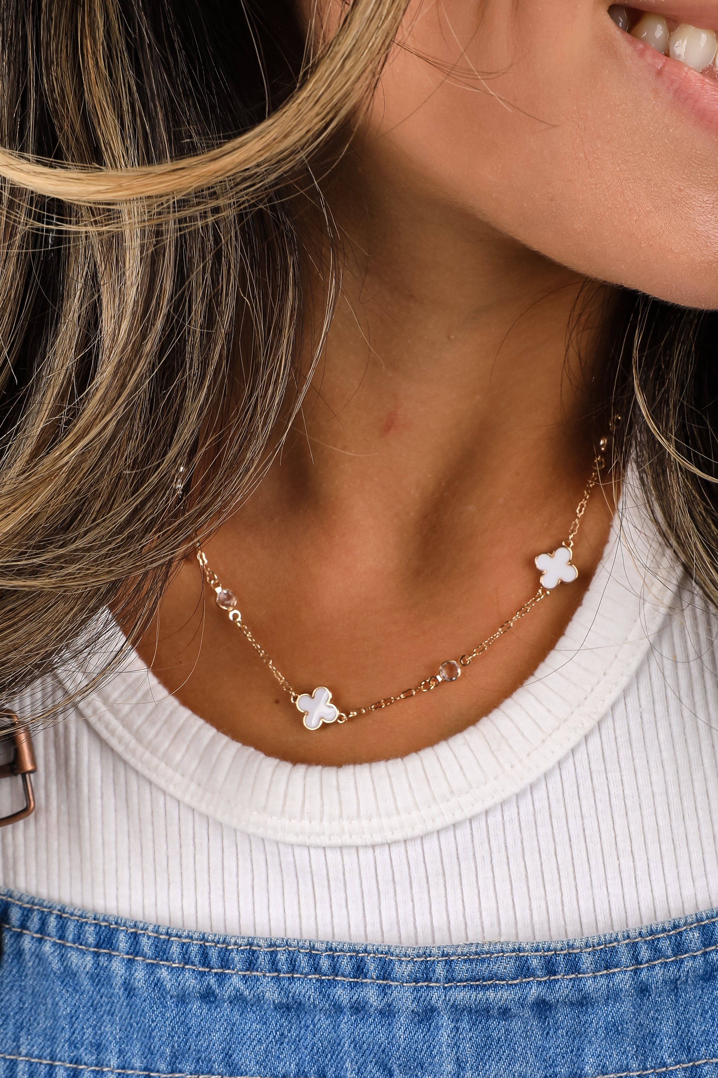 Close-up of a person wearing a delicate necklace with floral pendants.