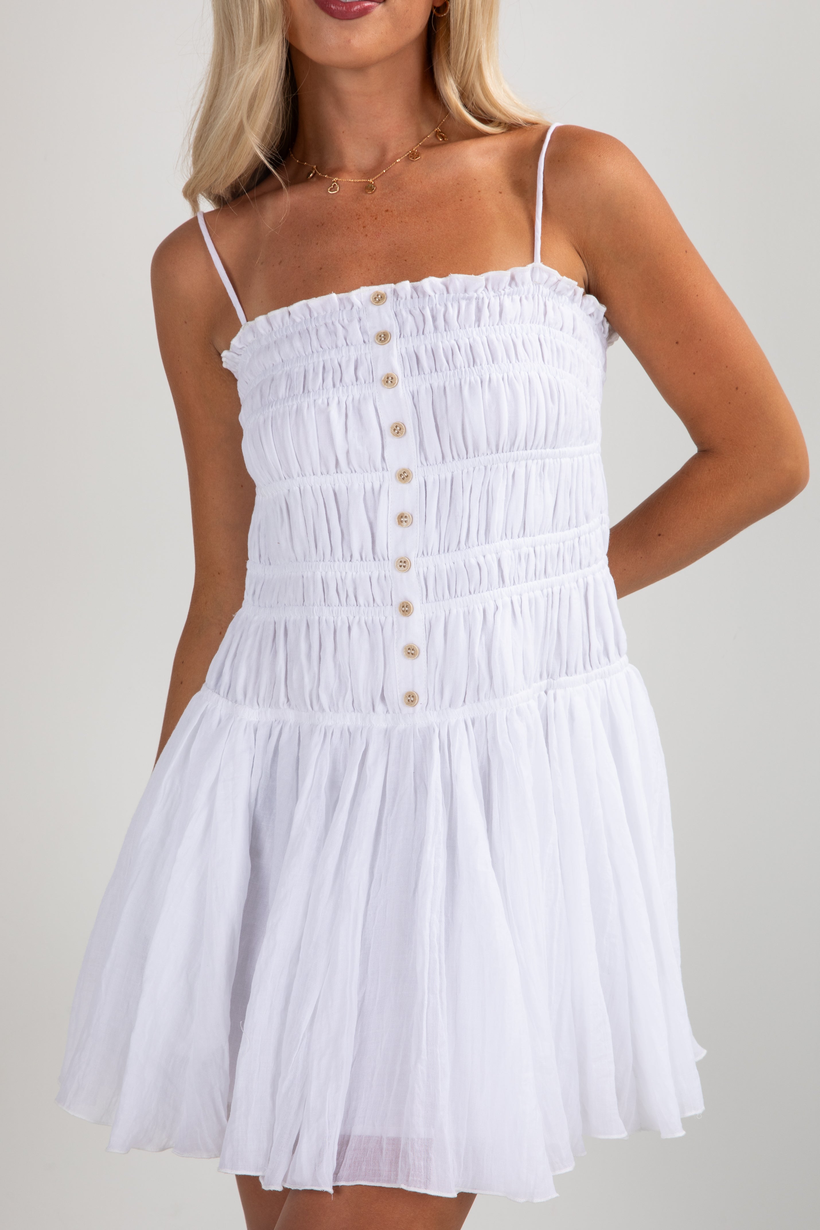 White dress with button details worn by a model on a plain background