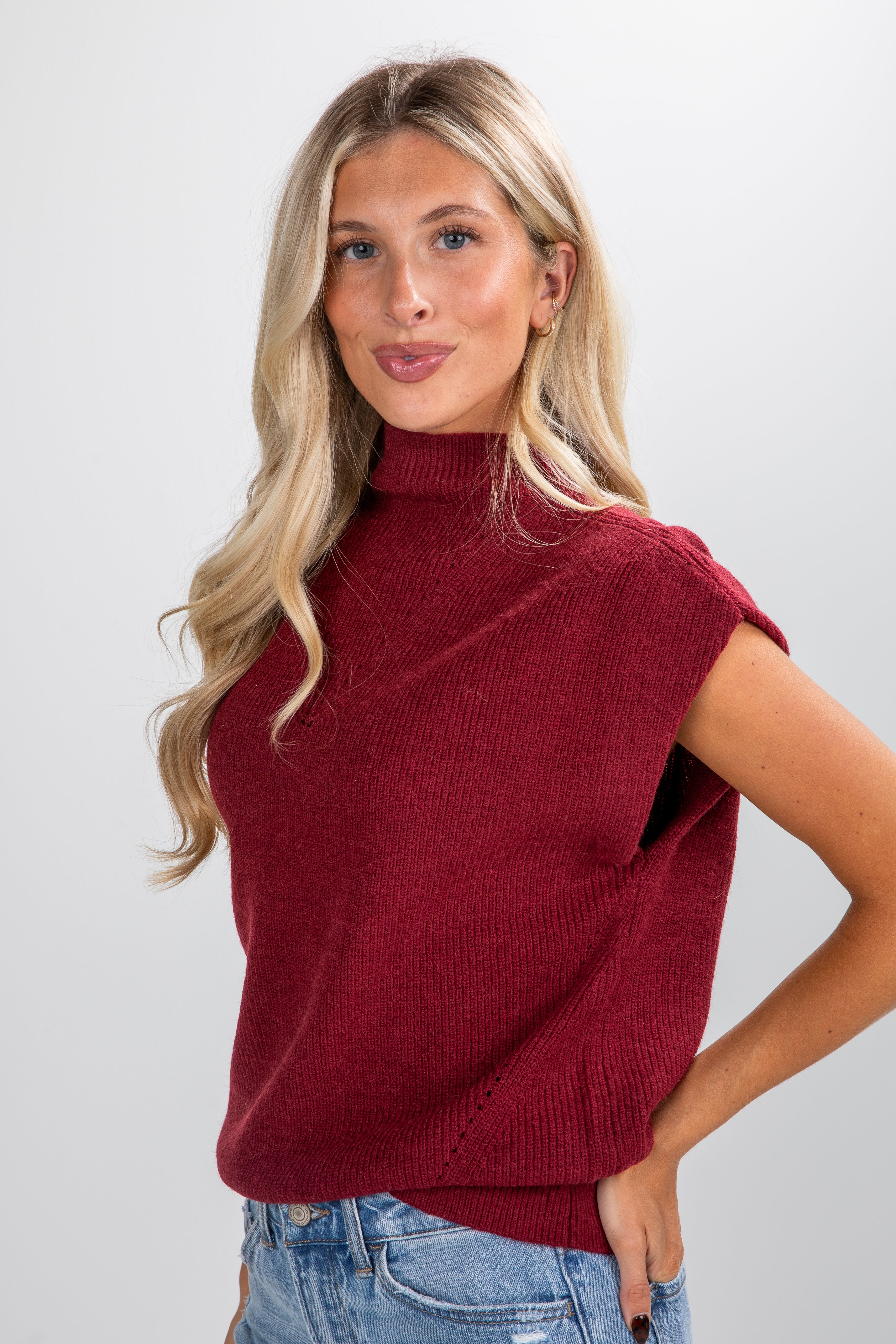 Woman wearing a red sleeveless sweater against a white background