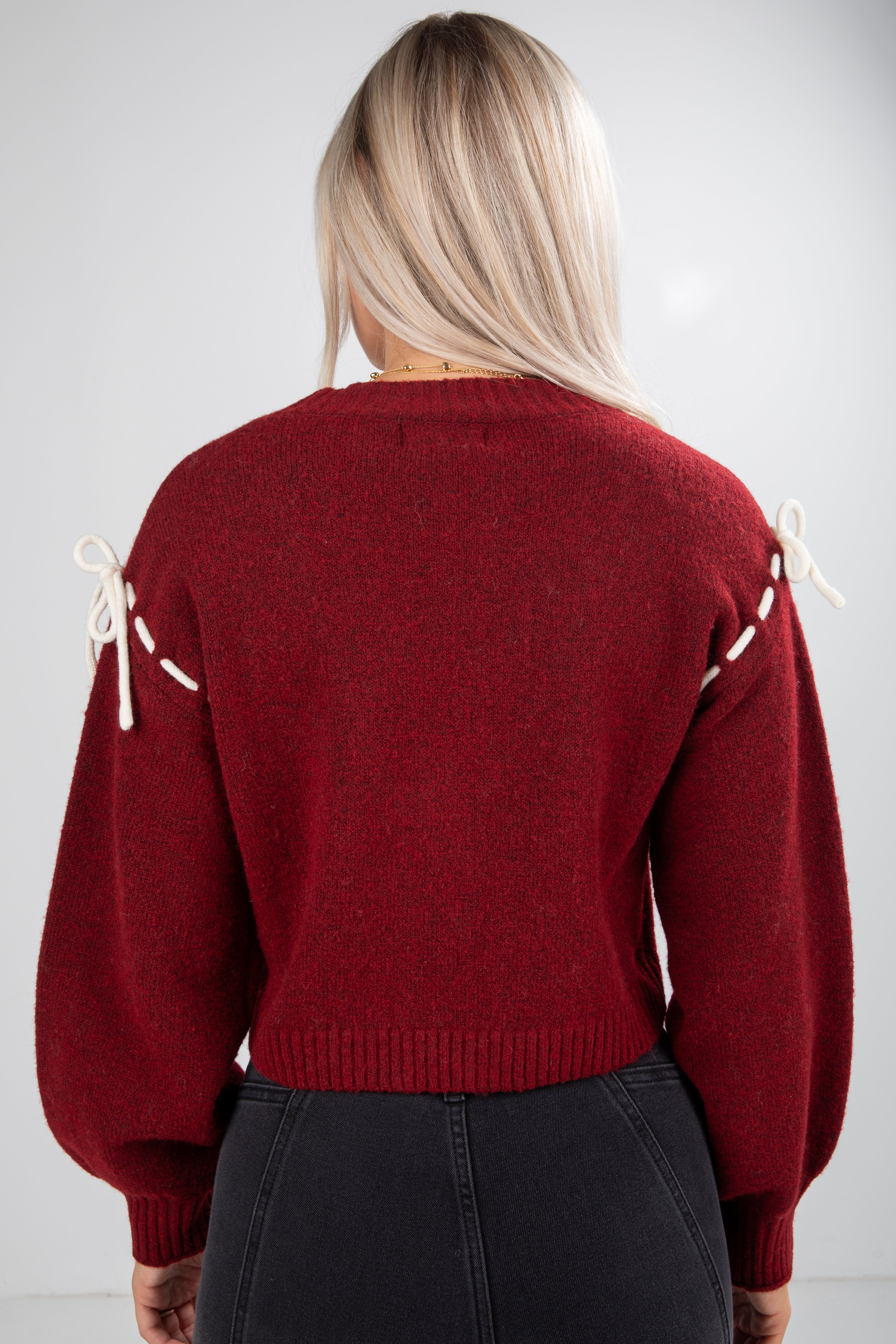 Red sweater with white lace details on a plain background