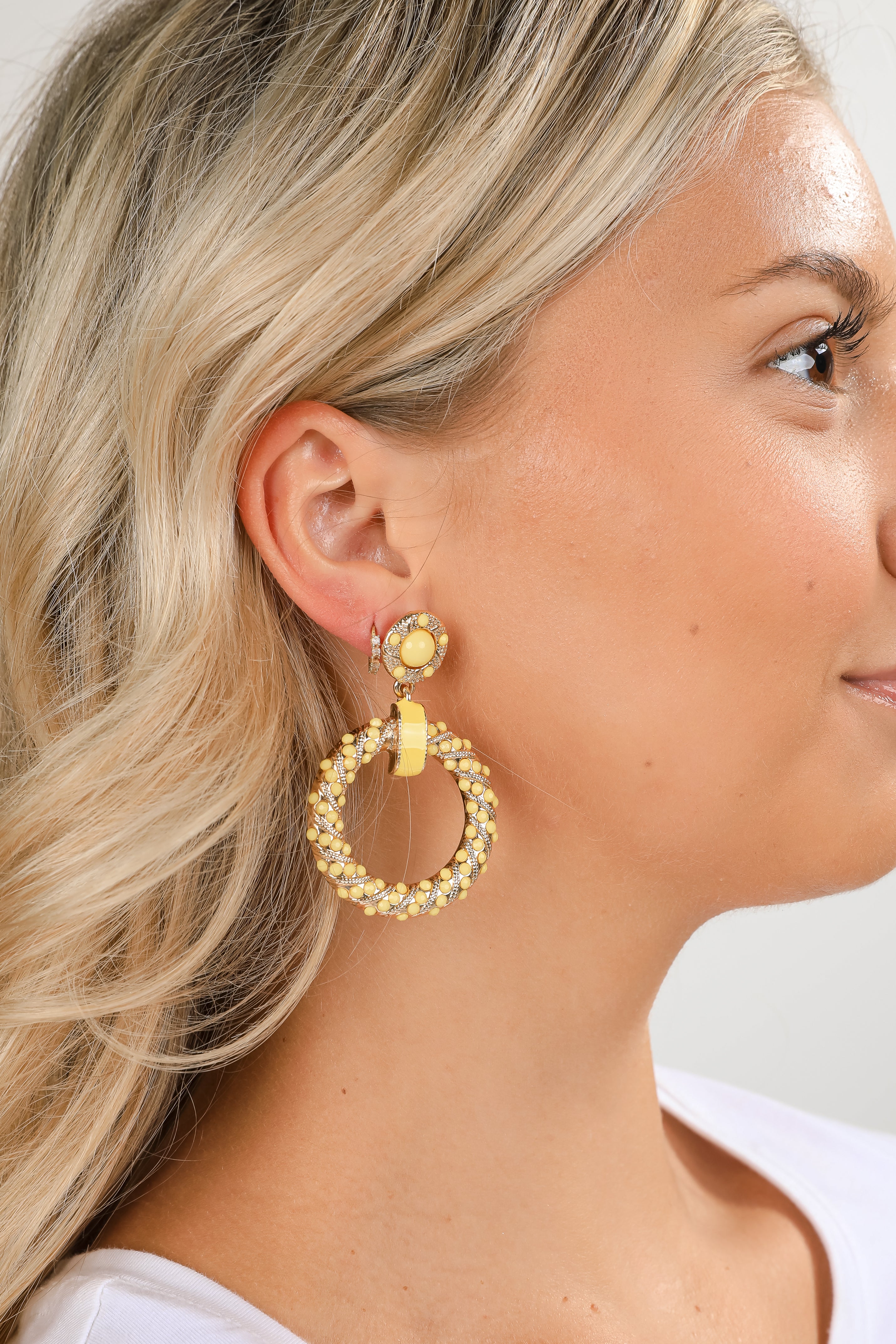 Close-up of a woman wearing gold hoop earrings with a blurred background