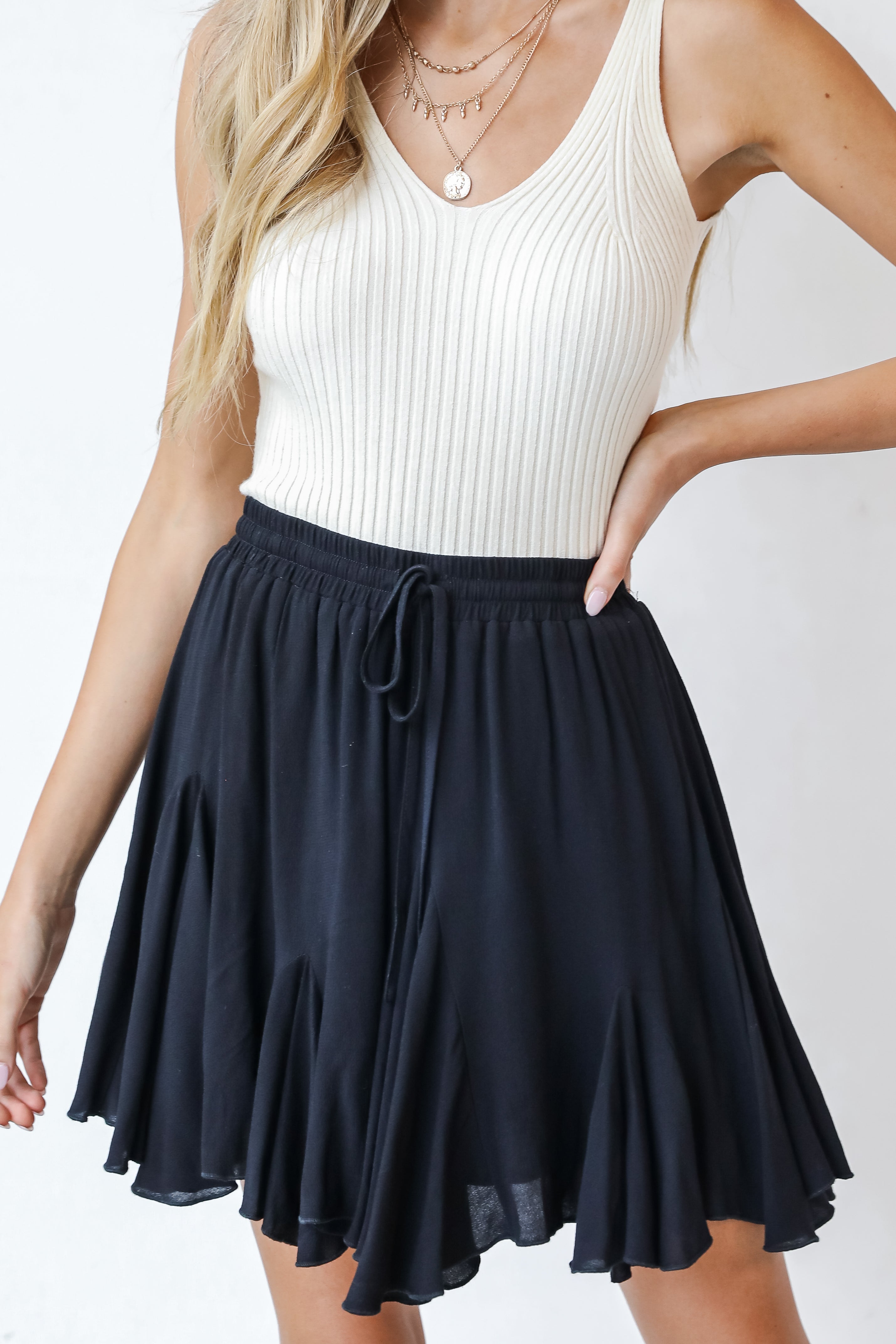 This cute skirt is designed with a lightweight woven knit. It features an elastic waistband with a functional drawstring and a flowy fit that ends at a mini length.