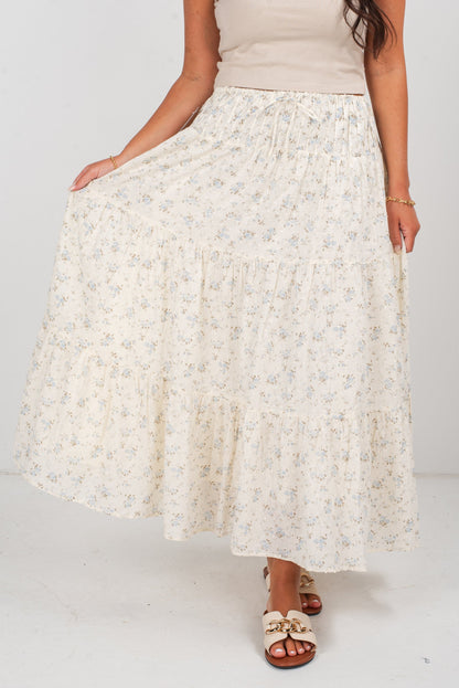 Woman wearing a long, light-colored floral skirt on a plain background