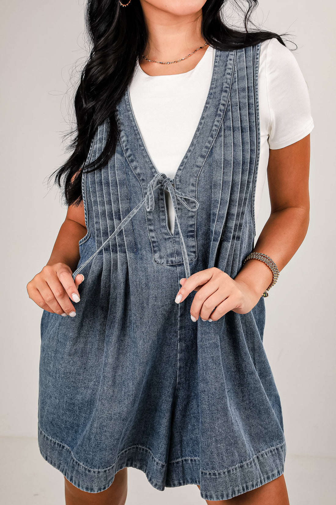 Woman wearing a denim dress over a white shirt on a plain background