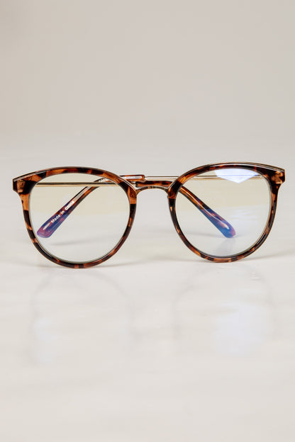 Tortoiseshell eyeglasses on a light beige background