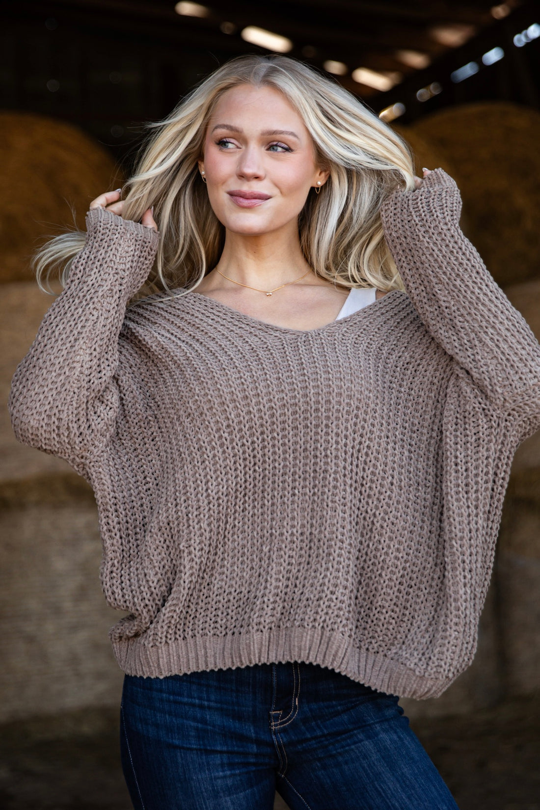 Woman wearing a chunky knit sweater with a neutral background