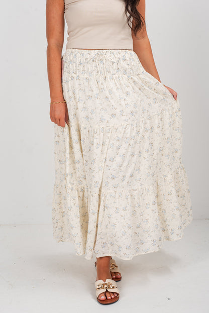Person wearing a long, light-colored floral skirt on a white background