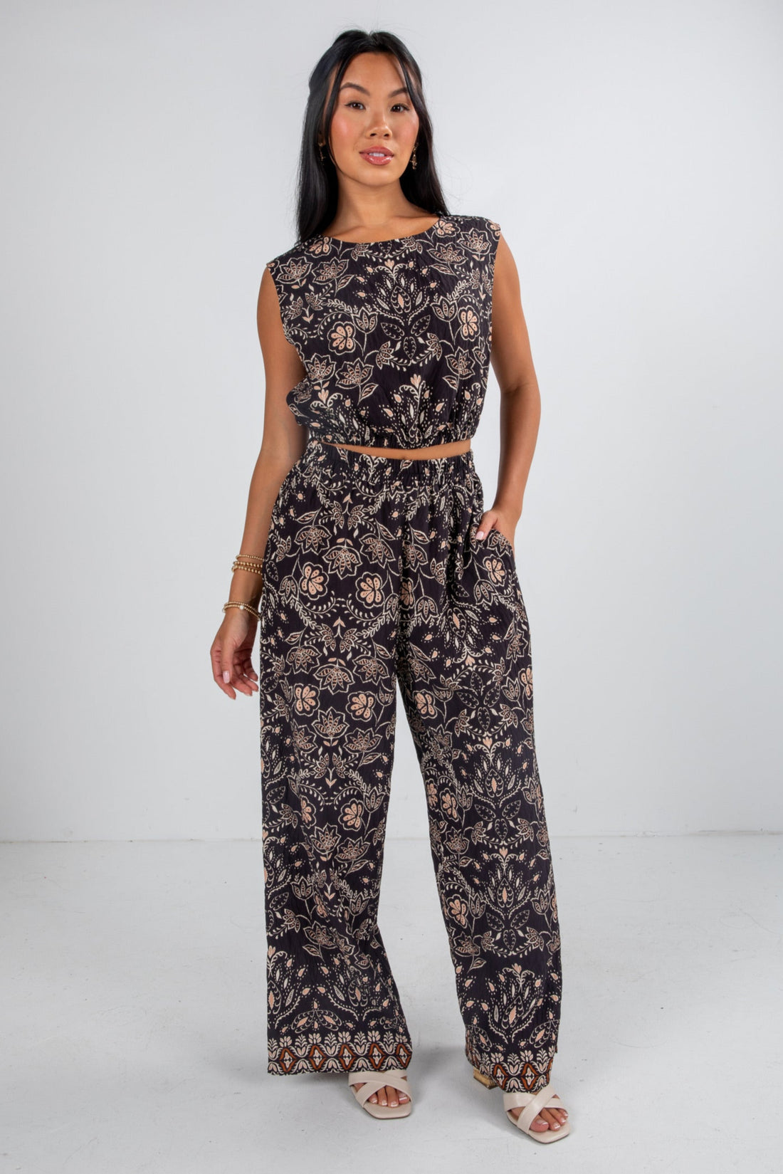 Woman wearing a black patterned top and pants on a white background