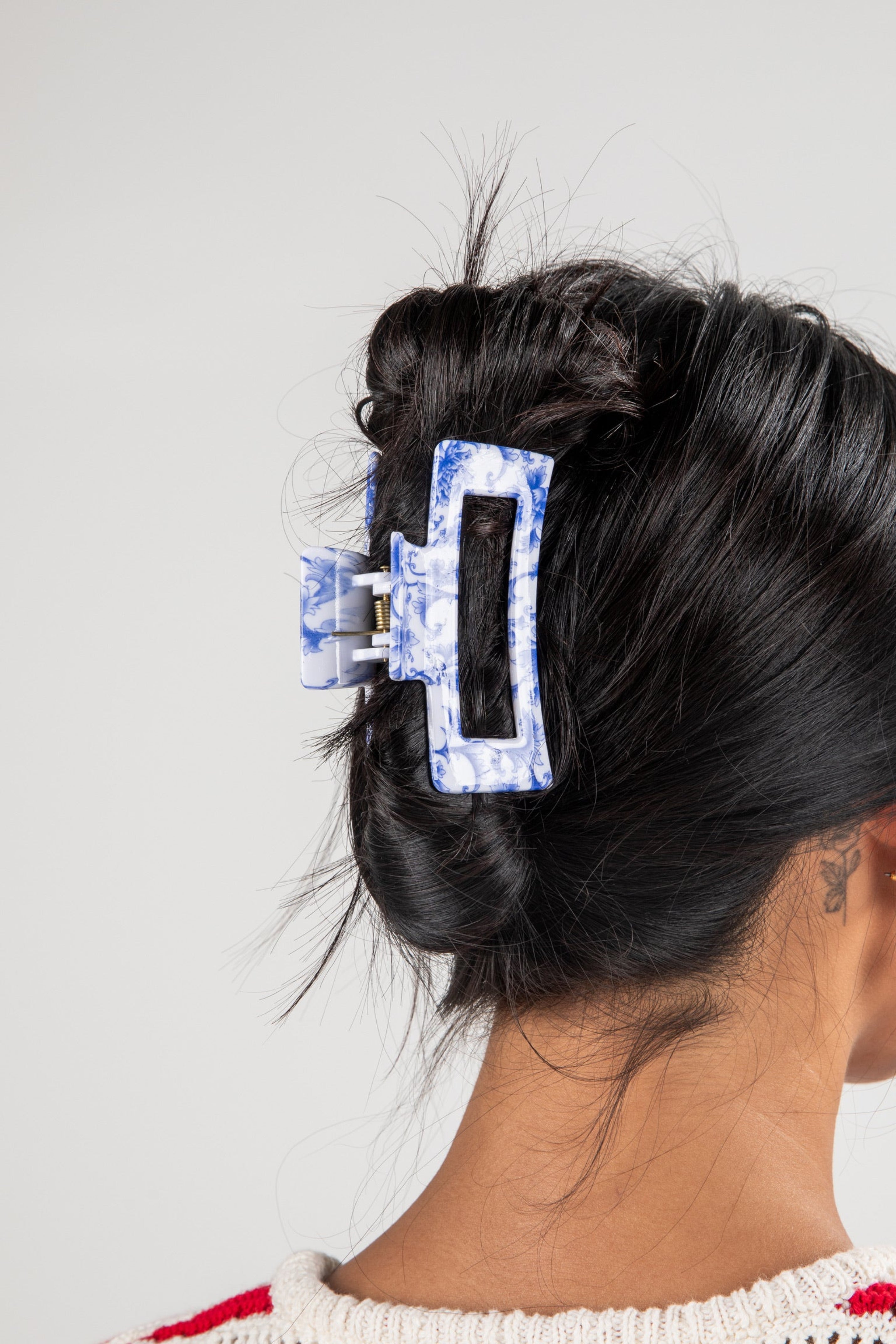 Person with a blue hair clip in their dark hair against a white background