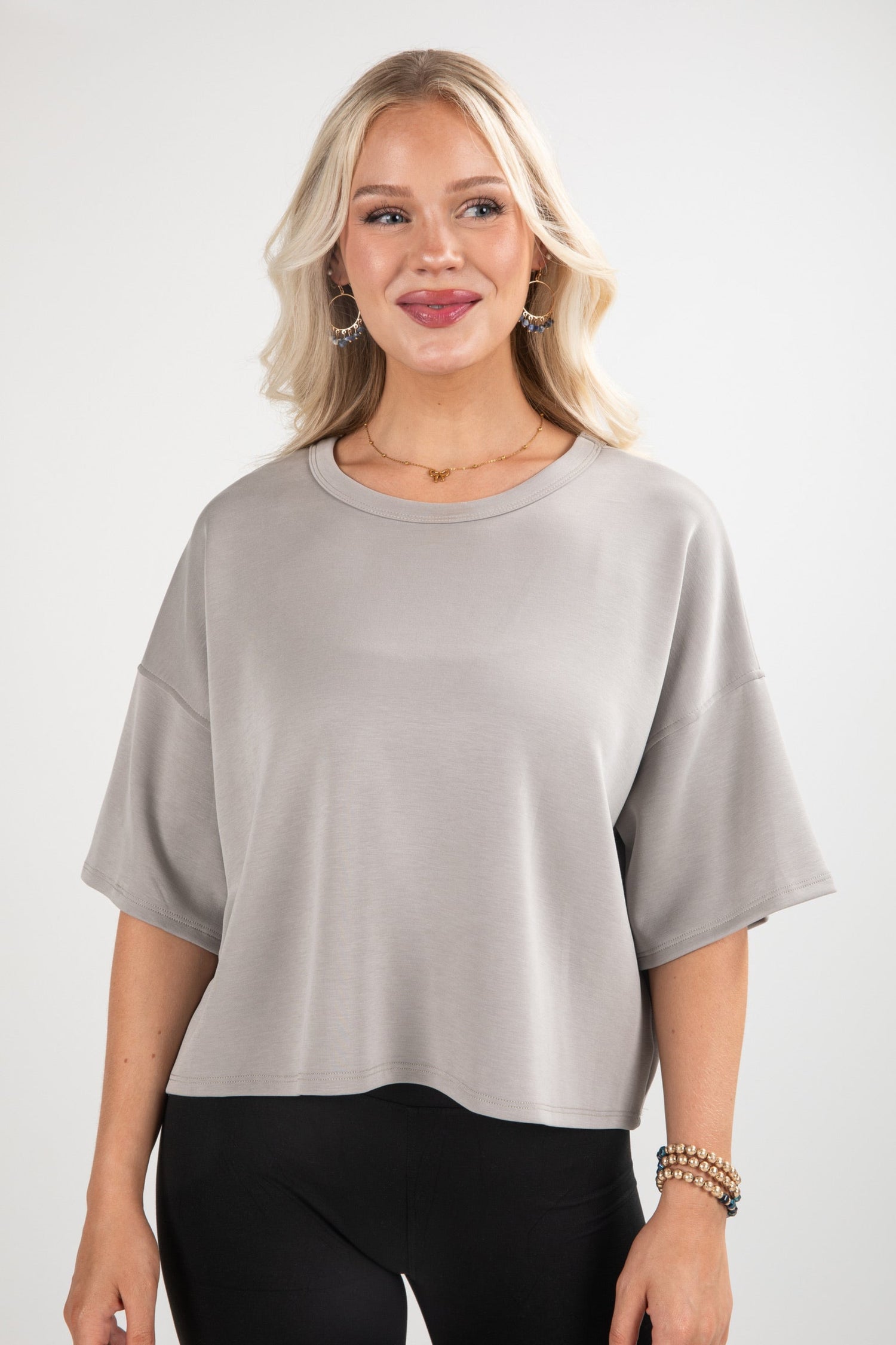 Woman wearing a gray oversized t-shirt and black pants on a white background