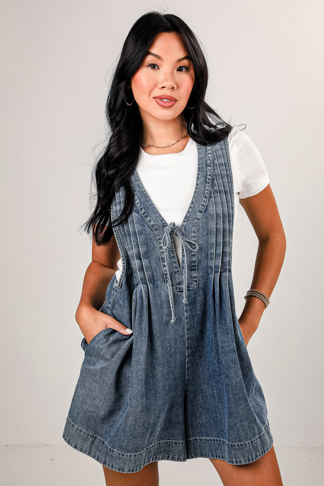 Woman wearing a denim dress over a white shirt on a plain background