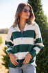 Woman wearing a green and white striped sweater in a tree farm setting