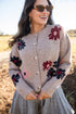 Woman wearing a floral-patterned cardigan in an outdoor setting