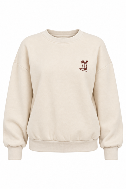 A cream-colored crewneck sweatshirt with a small embroidered mushroom graphic on the left chest, displayed on a clean white background.