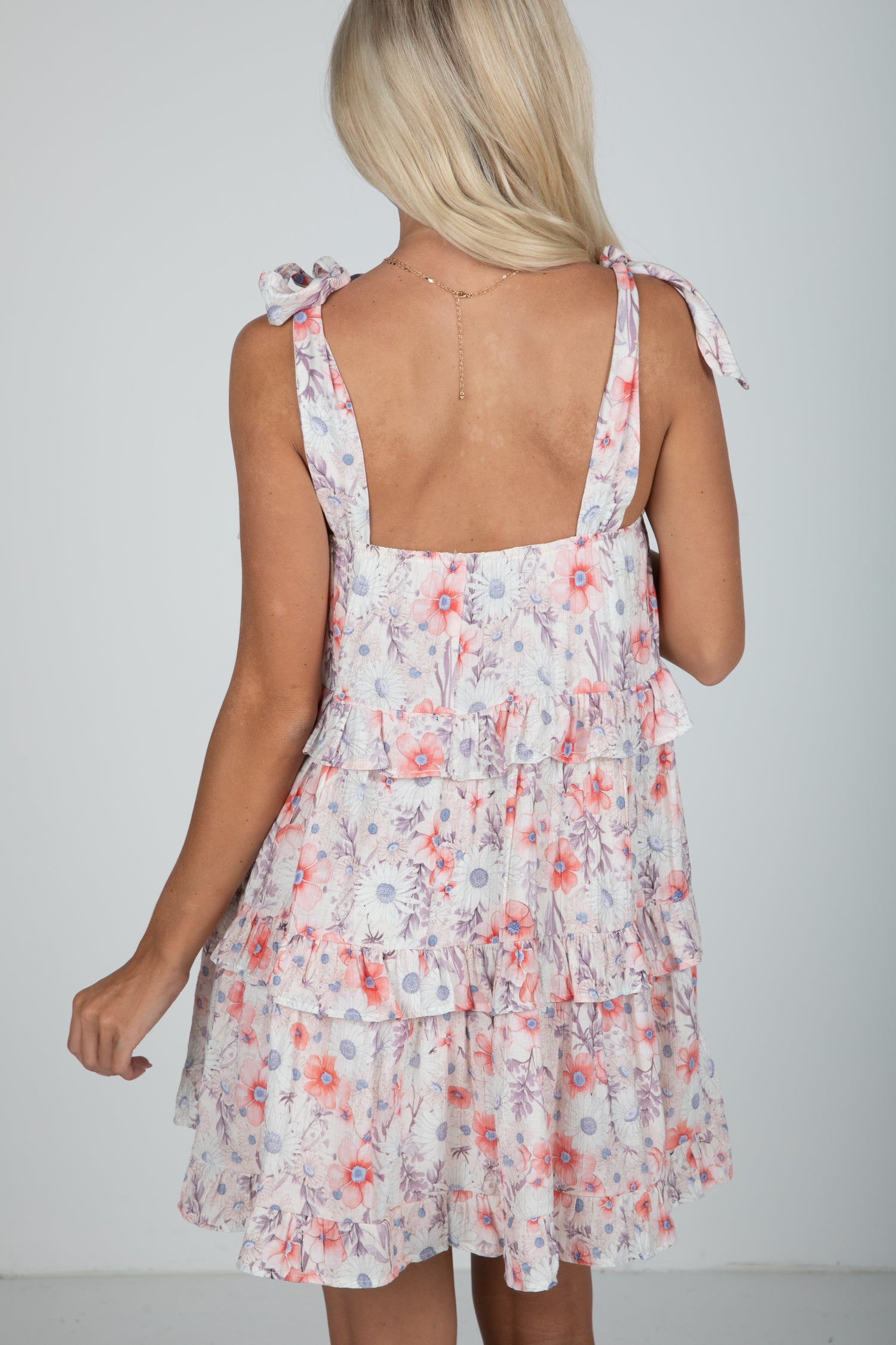 Woman wearing a floral dress with thin straps on a plain background