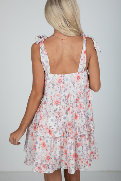 Woman wearing a floral dress with thin straps on a plain background