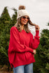 Woman wearing a red sweater and white beanie in a Christmas tree lot
