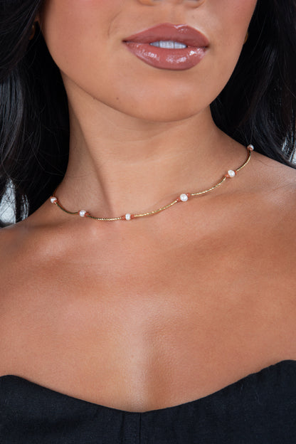 Close-up of a woman wearing a delicate pearl necklace with a blurred background