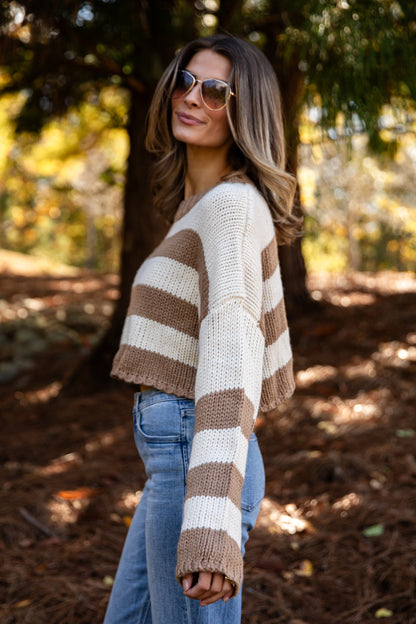Woman wearing a striped sweater and sunglasses in a forest setting