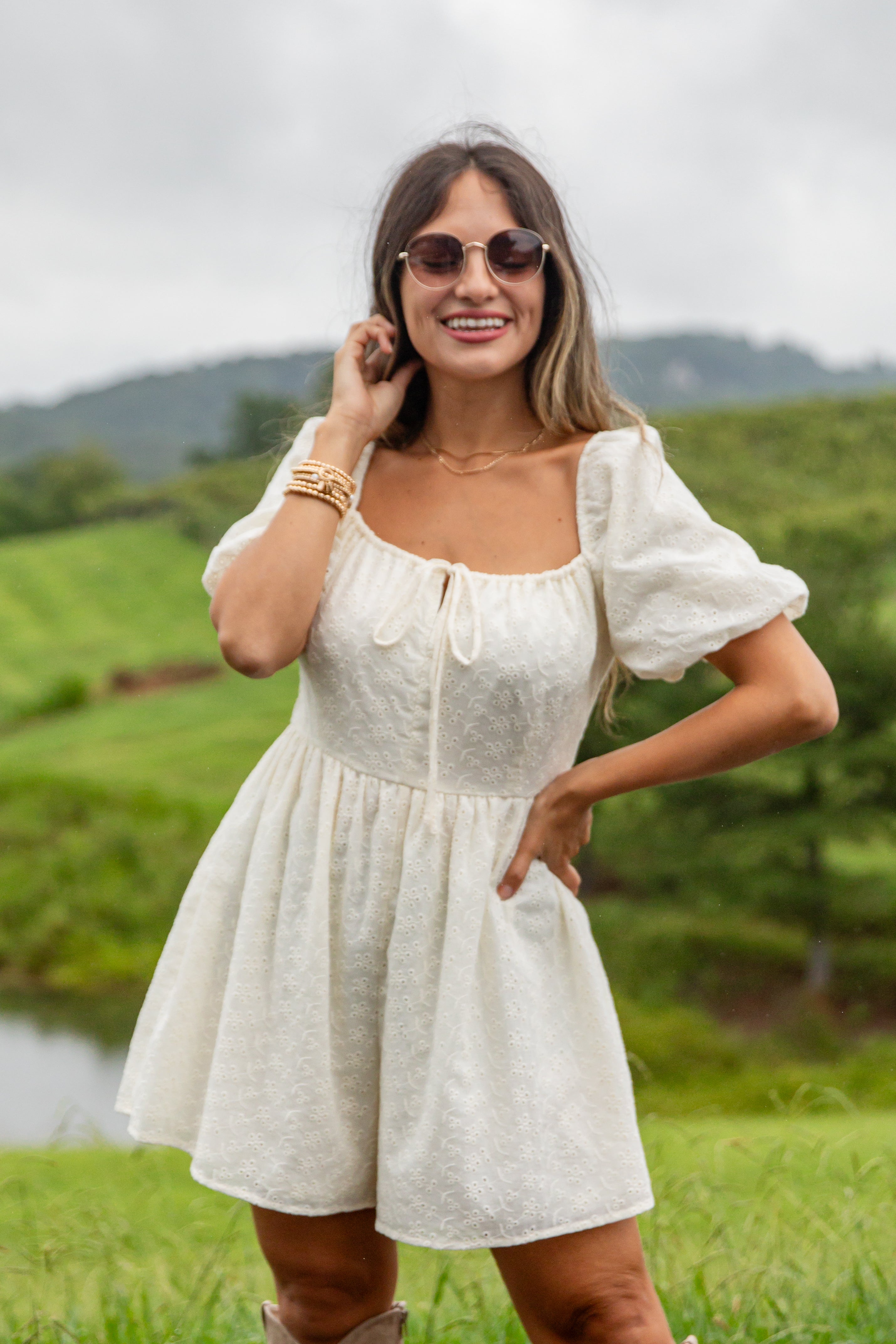 Woman in a white dress standing outdoors with greenery in the background