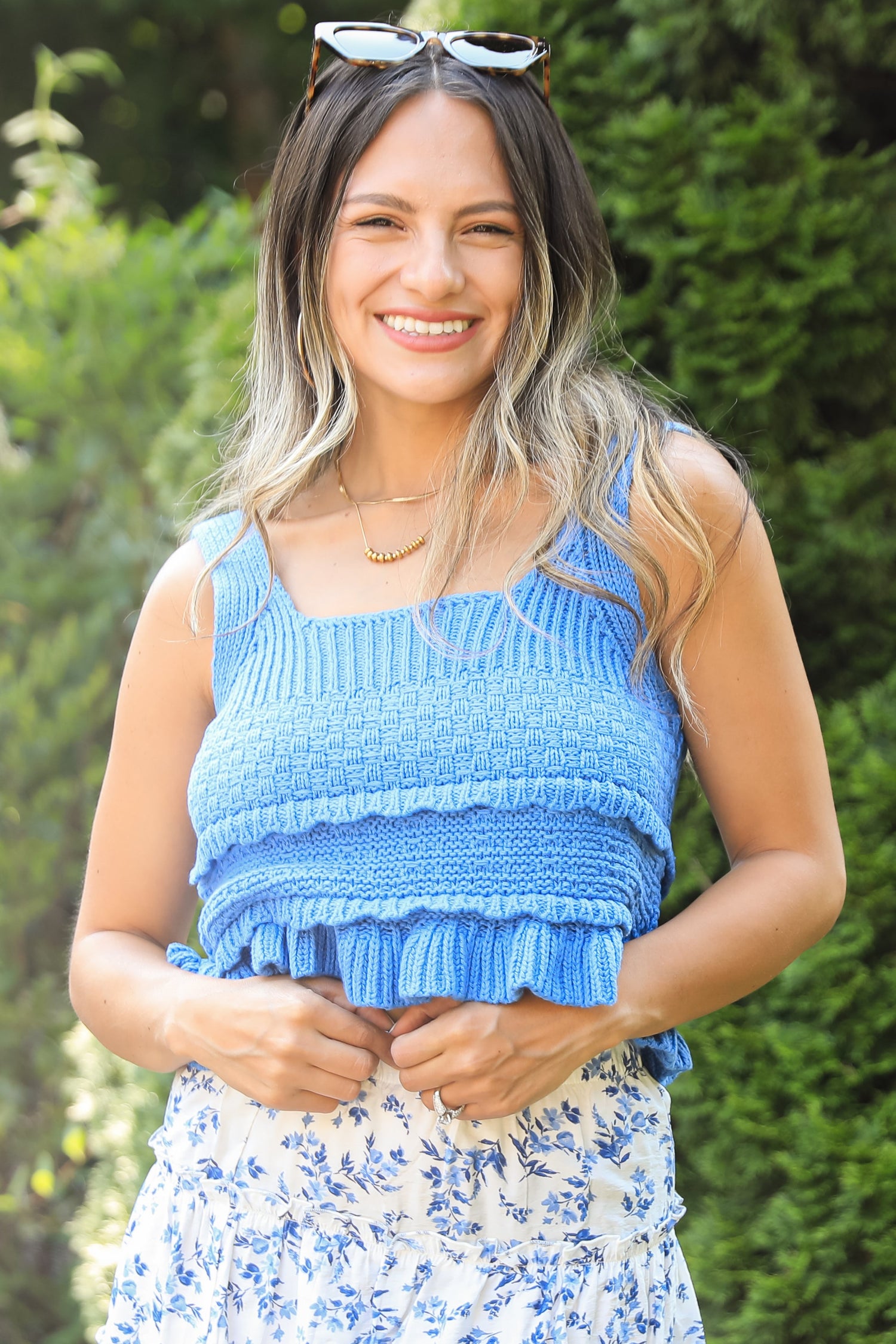 Woman wearing a blue ruffled top and floral skirt outdoors