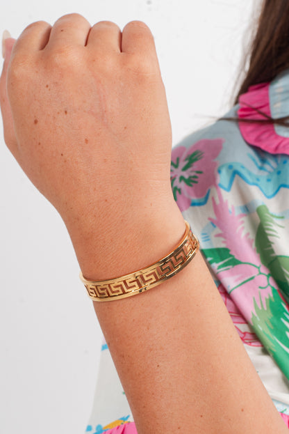 Gold bracelet on a wrist with a colorful background