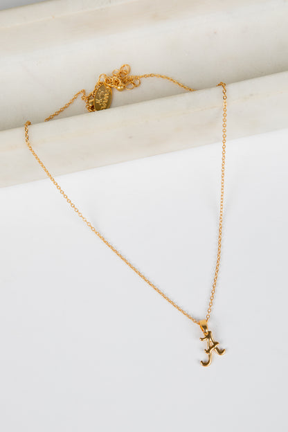 Gold necklace with a pendant on a white surface