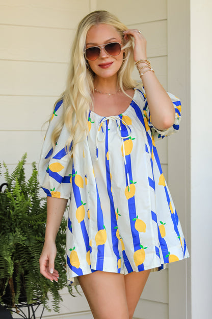 Woman wearing a colorful dress with a lemon pattern outdoors.