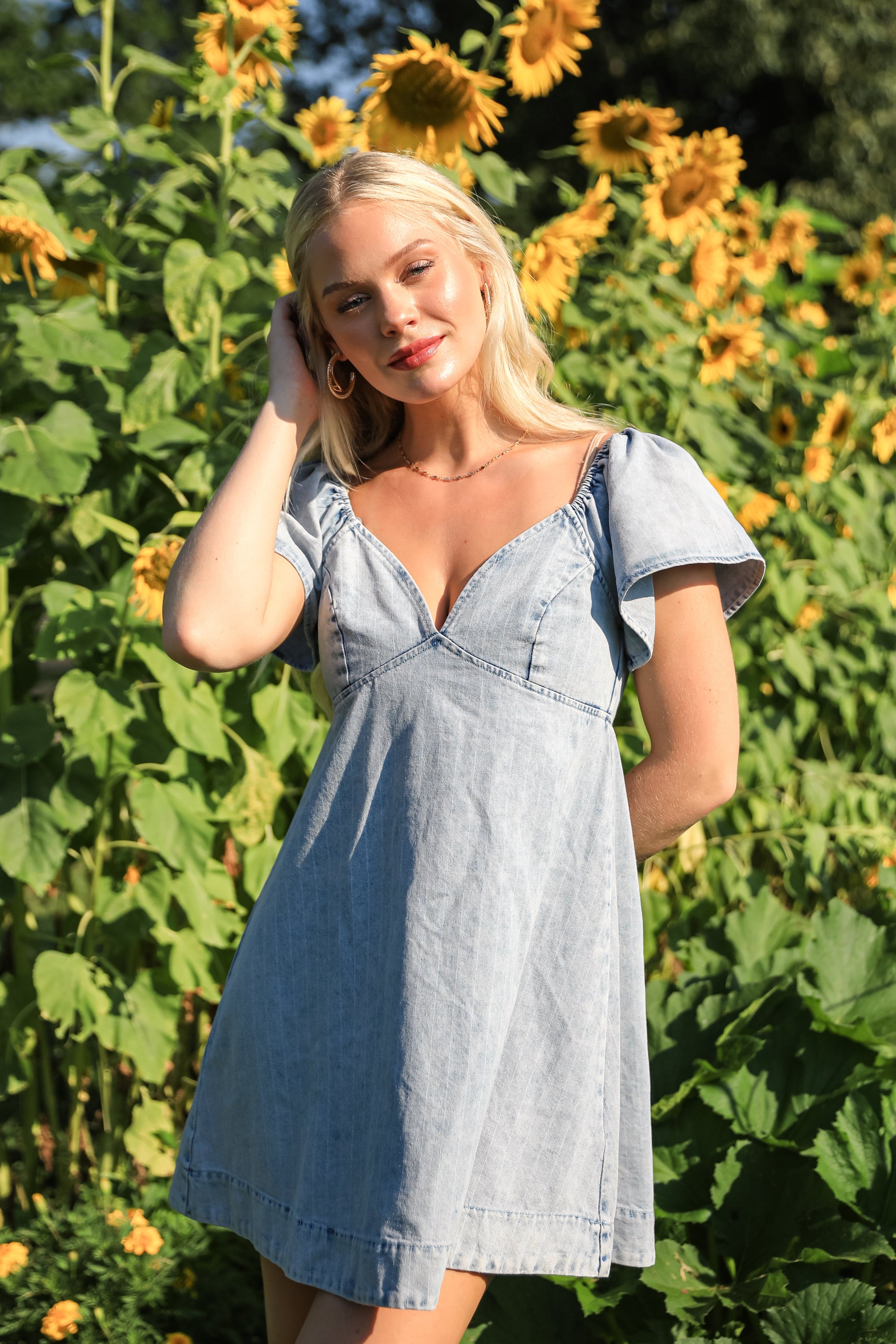 Woman in a denim dress standing in a sunflower field