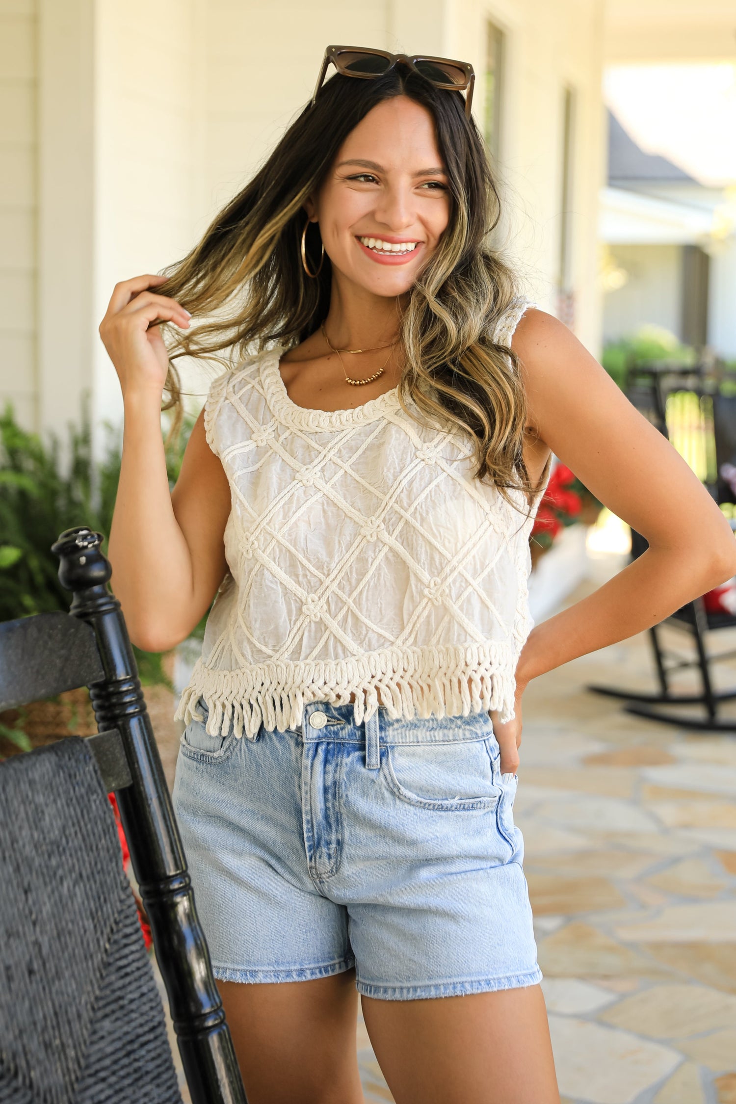 Woman wearing a white lace top and denim shorts outdoors.