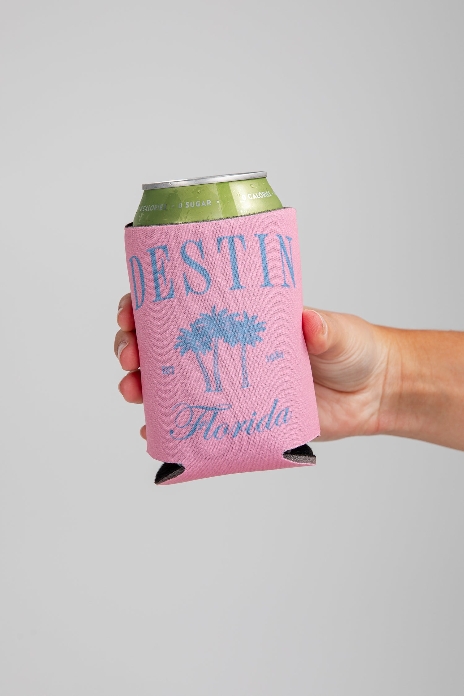 Hand holding a pink can cooler with &