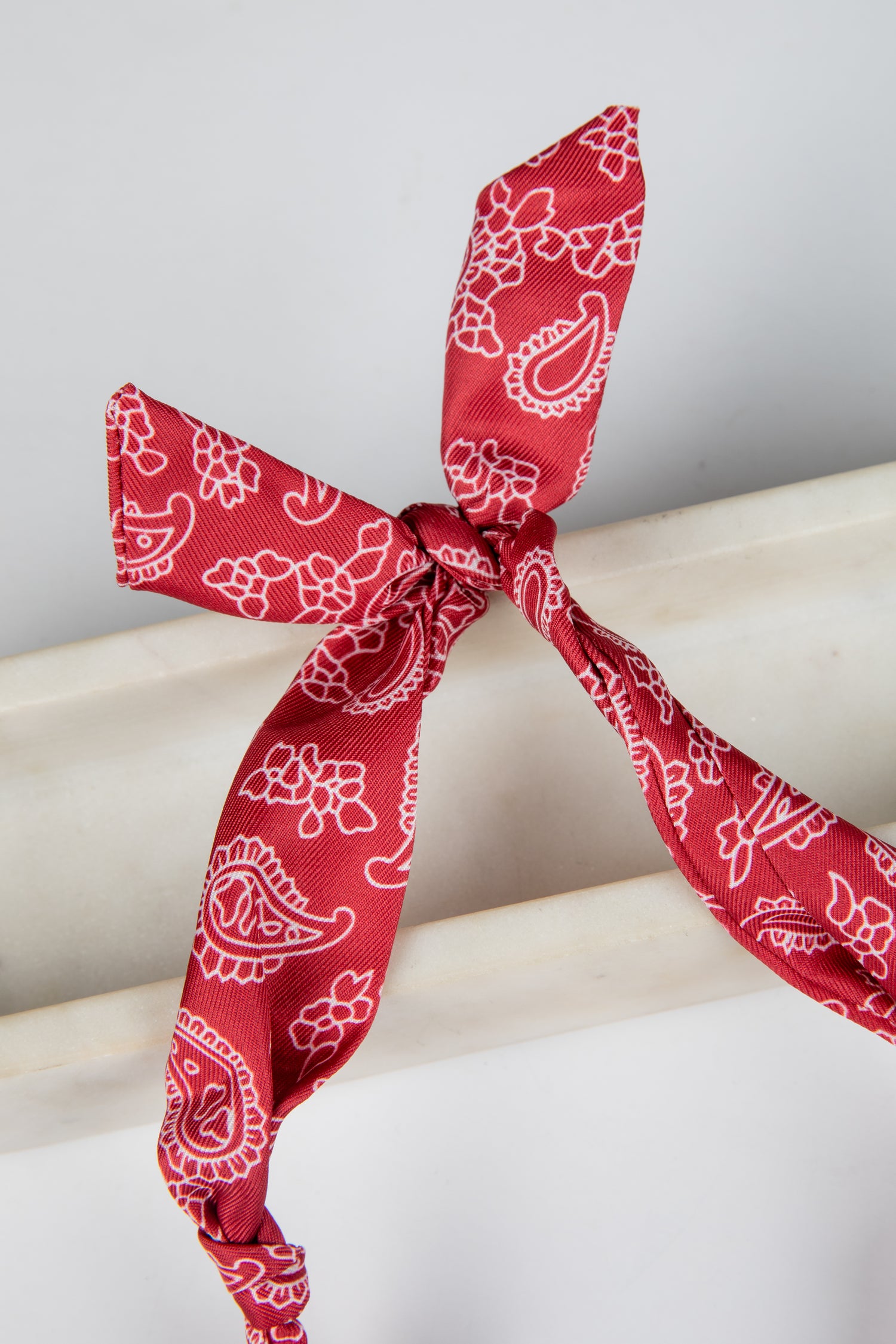 Red bandana with white patterns tied on a white surface