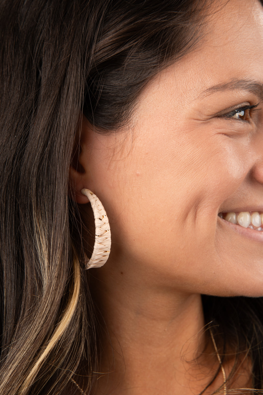 Close-up of a woman wearing a gold hoop earring with a blurred background