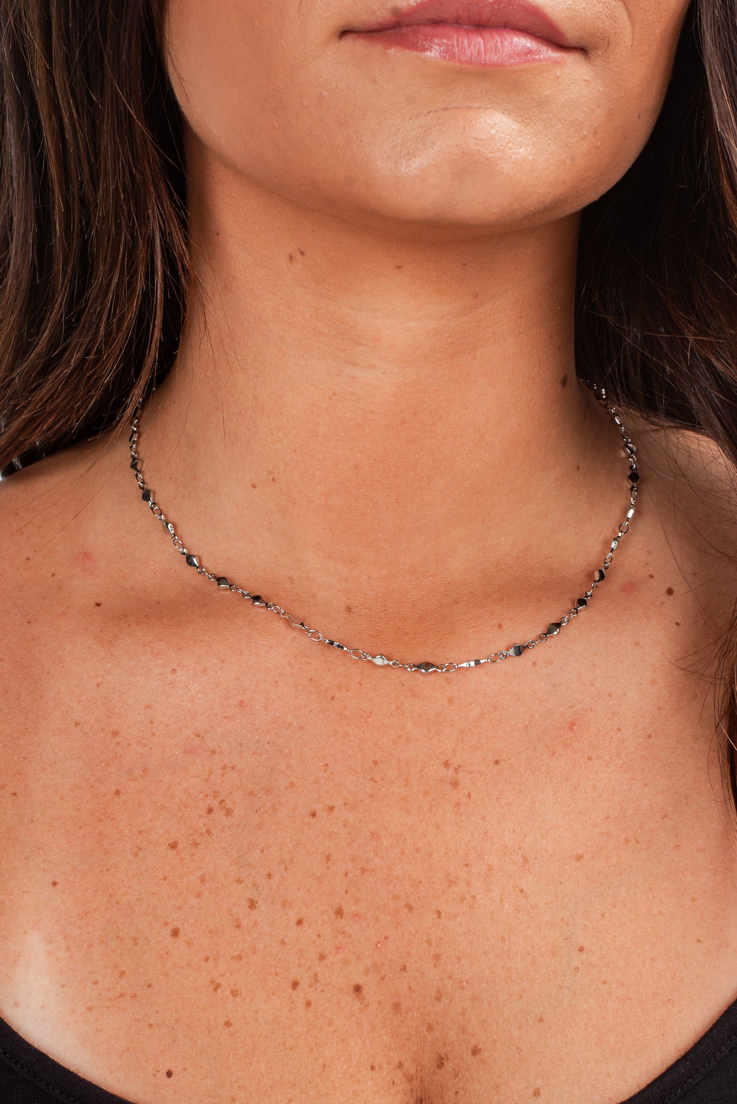 Close-up of a person wearing a delicate necklace with a blurred background