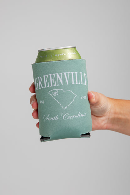 Hand holding a can with a Greenville, South Carolina design on a gray background