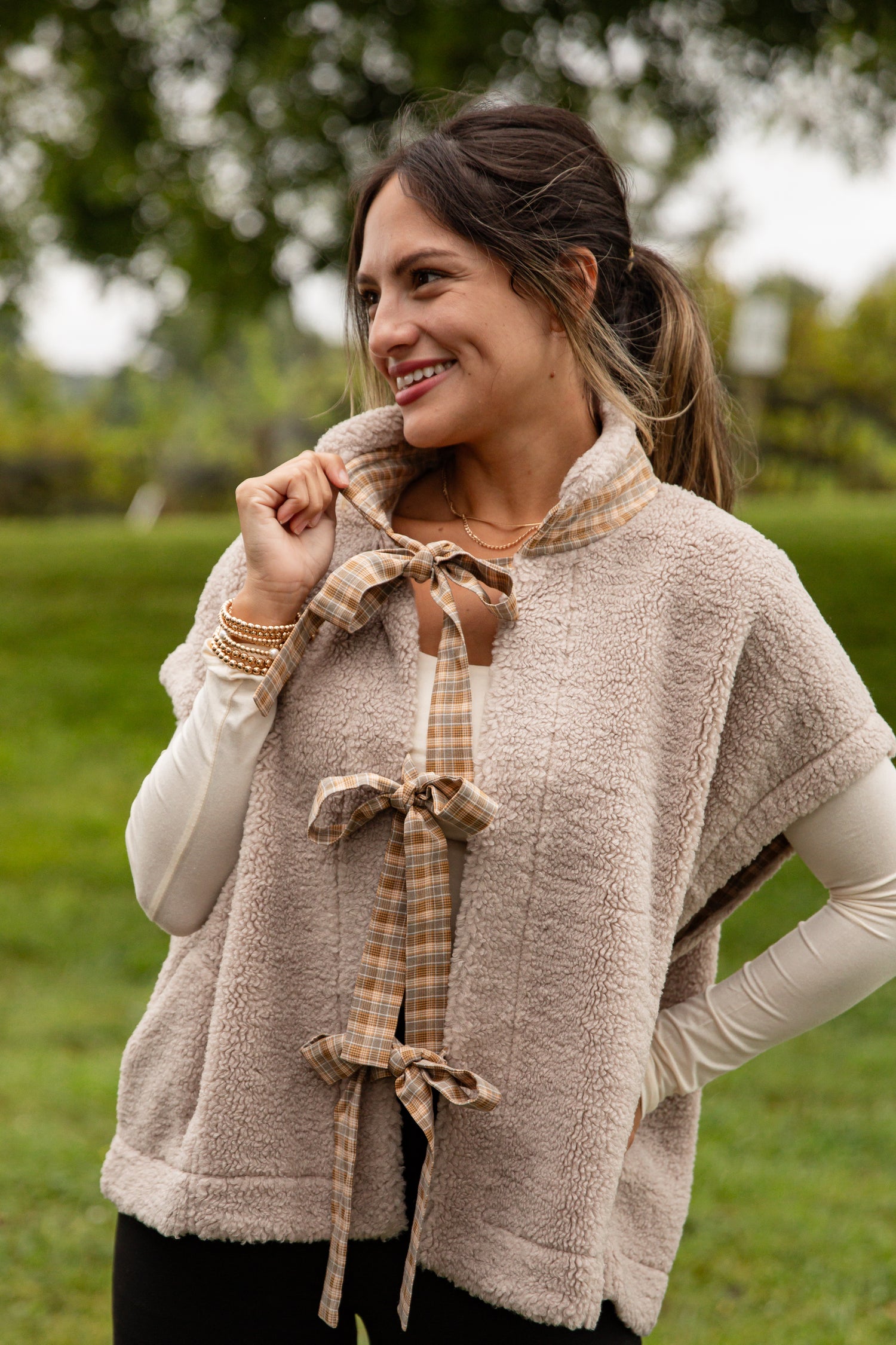 Woman wearing a beige vest with plaid accents outdoors