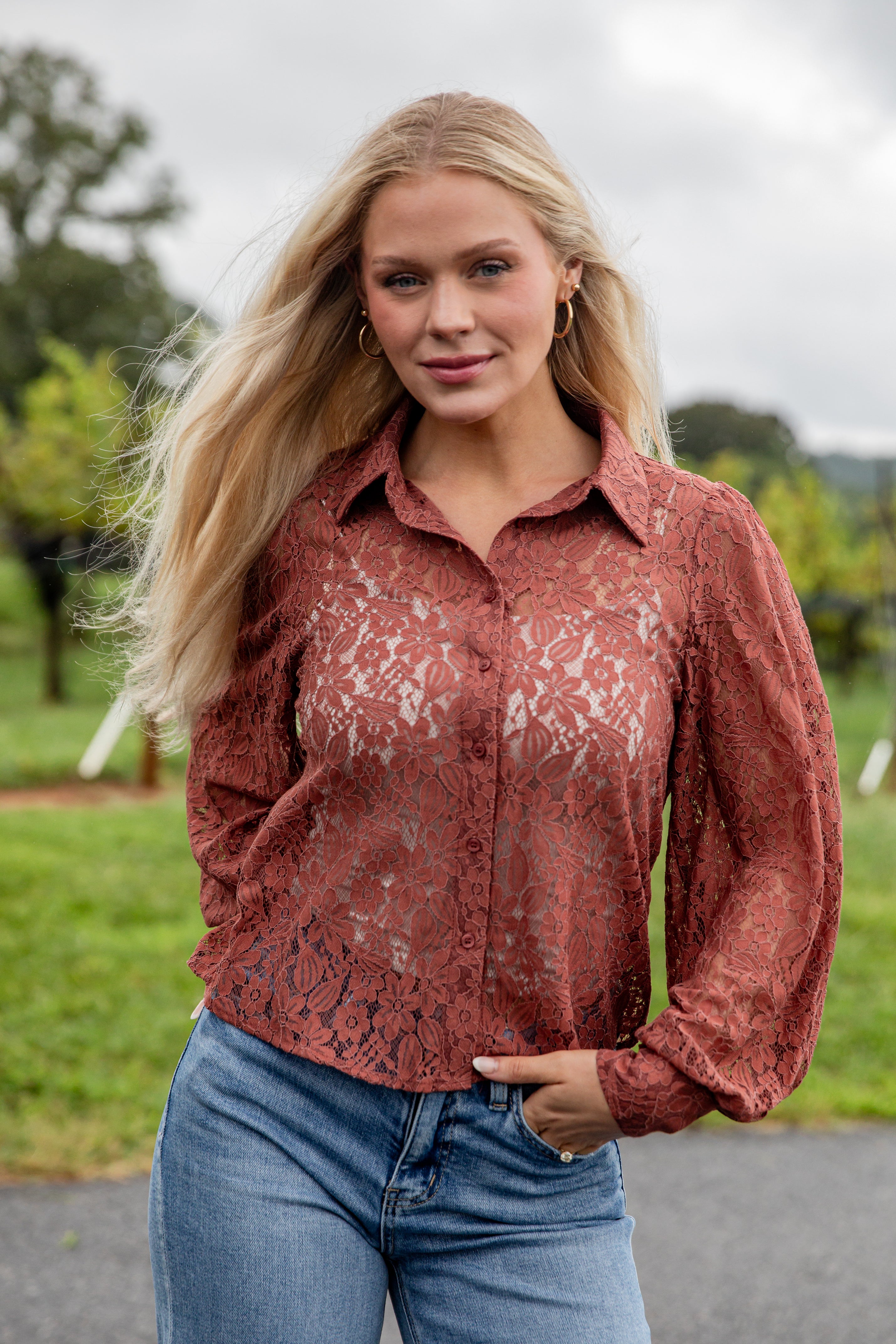 Woman wearing a red lace blouse and blue jeans outdoors