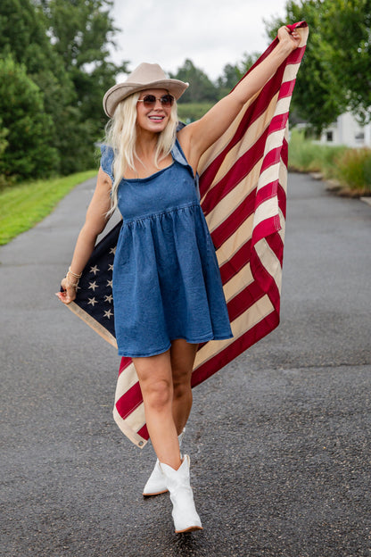 Woman holding an American flag on a road with trees in the background