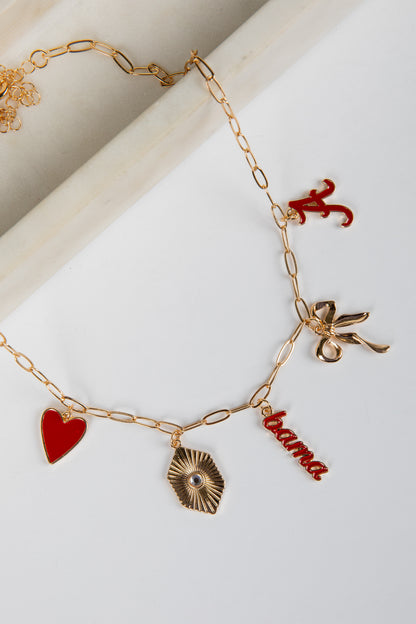 Gold bracelet with various charms including a red heart, leaf, and &