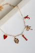 Gold bracelet with various charms including a red heart, leaf, and &