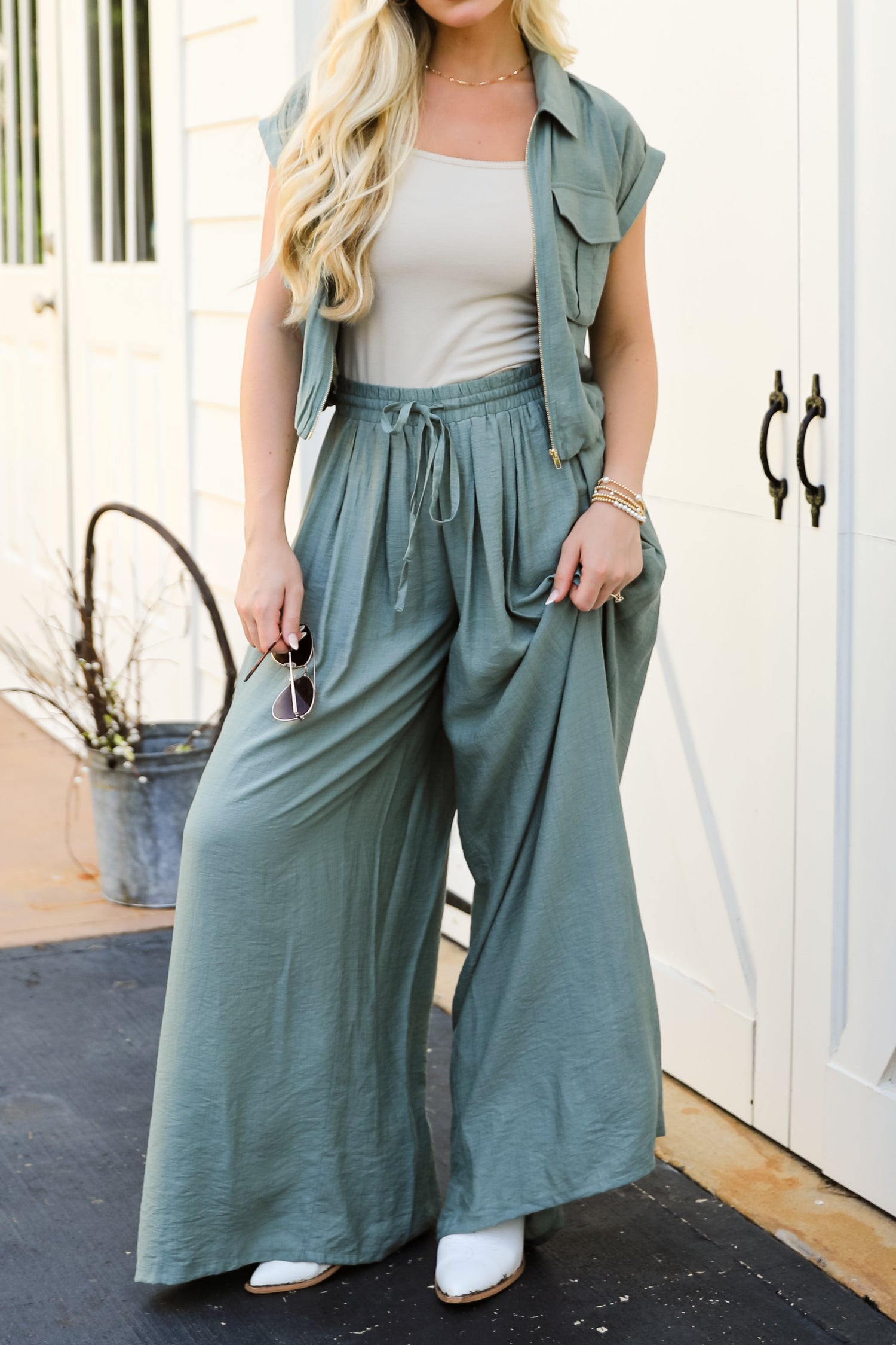 Woman wearing a green outfit with wide-leg pants and a jacket on a black mat.