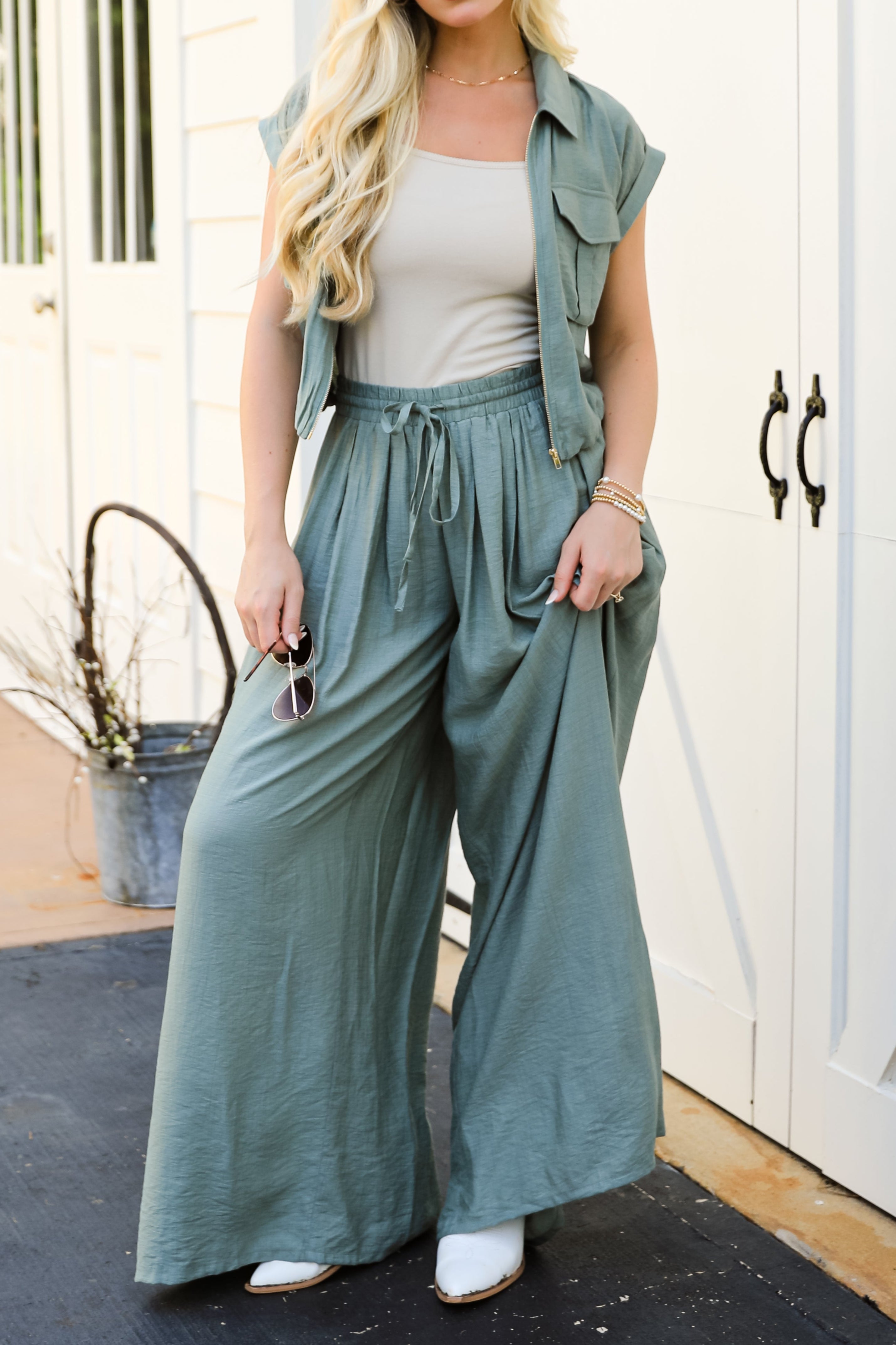 Woman wearing a green outfit with wide-leg pants and a jacket on a black mat.